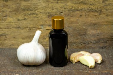 Şişede sarımsak yağı ve ahşap zemin üzerinde taze sarımsak.. 
