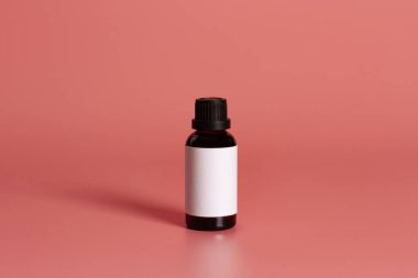 Pembe arkaplan üzerinde boş etiket maketi olan şişe.