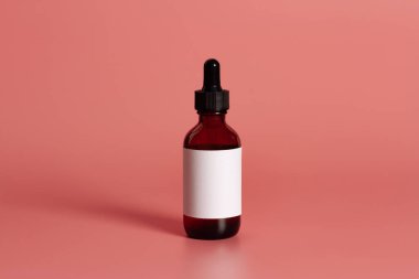 Pembe arkaplan üzerinde boş etiket maketi olan şişe.