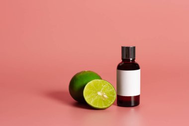 İçinde boş etiket maketi ve pembe arka planda taze limon olan bir şişe. Temel petrol konsepti.