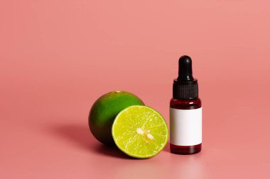 İçinde boş etiket maketi ve pembe arka planda taze limon olan bir şişe. Temel petrol konsepti.