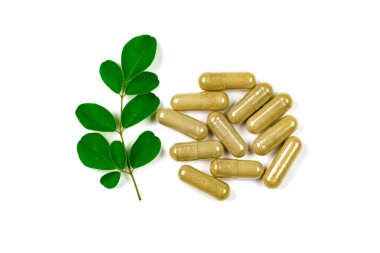 Moringa oleifera kapsülü ve beyaz arkaplanda yalıtılmış moringa yaprağı.