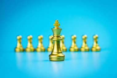 Altın kral satranç figürü mavi arka planda birden fazla altın piyon figürü önünde duruyor, liderlik kavramı.. 