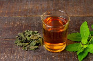 Tulsi ya da şeffaf fincanda taze ve kuru tül yaprağı ve kırsal ahşap arka planda kutsal fesleğen çayı. Hindistan 'da Ayurvedic tıp. Sağlık için iç..