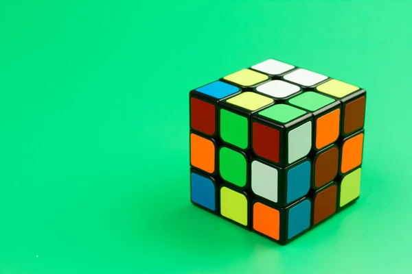SAMUT-SAKHON, THAILAND - 17 Nisan 2022: Rubik küp bulmacası yeşil arka planda izole edilmiş,.