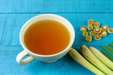 Mavi ahşap arka planda dilimlenmiş yeşil yapraklı bir fincan sıcak limon otu çayı. Sağlıklı bitkisel içecek konsepti için limon otu.