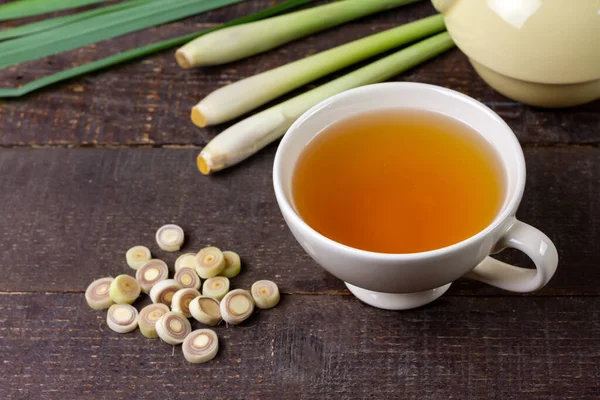 Kahverengi ahşap arka planda dilimlenmiş yeşil yapraklı bir fincan sıcak limon otu çayı. Sağlıklı bitkisel içecek konsepti için limon otu.