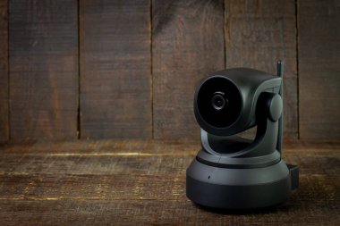 Ahşap arka planda siyah IP kamerası. Ev ve ofis için CCTV güvenlik kamerası, boşluğu kopyala.