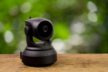 Black IP Camera on wooden with blur background. CCTV security camera for home or office.