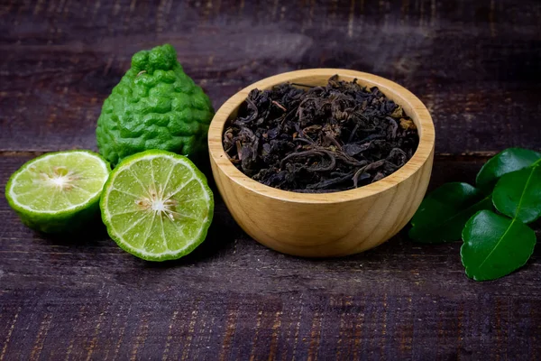 Bergamot tea or Earl Grey tea in wooden bowl and fresh bergamot fruit on rustic wooden background, top view.