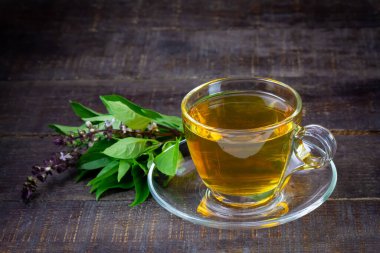 Basil tea in transparent cup with green leaf on rustic wooden table. Basil is food and herb for healthy.