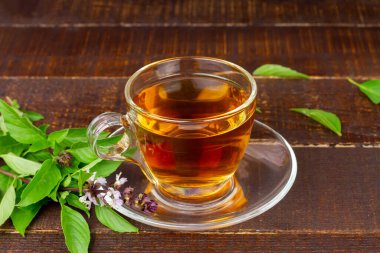 Basil tea in transparent cup with green leaf on rustic wooden table. Basil is food and herb for healthy.