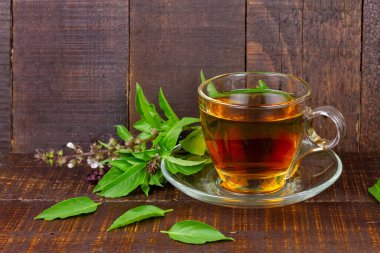 Basil tea in transparent cup with green leaf on rustic wooden table. Basil is food and herb for healthy.