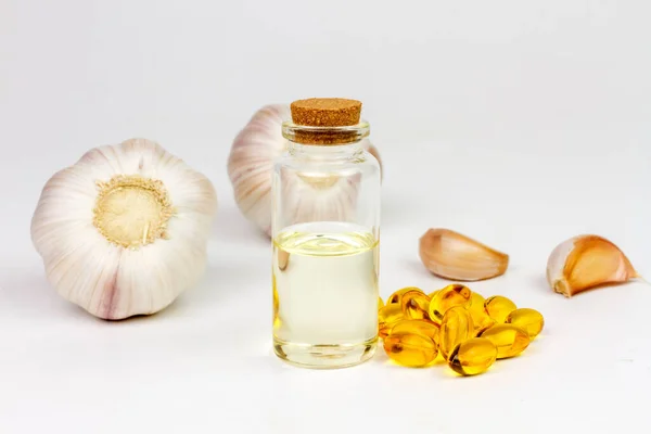 Garlic oil in transparent bottle with Garlic oil capsule soft gel on rough surface background.