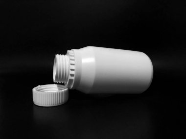 The empty plastic white bottle is on a dark background.