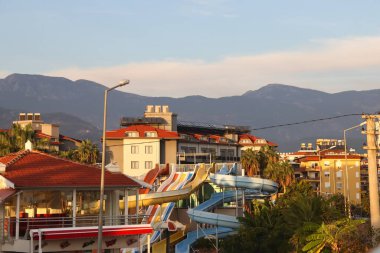 Türkiye 'de Alanya' da Kasım 2021 'de dağların arka planında su kaydırakları bulunan bir otel..