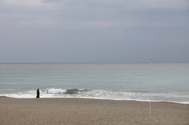 Yalnız figür, kumlu sahil ve denizin arka planında, minimalizm, huzur verici arka plan.