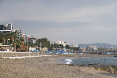 Issız bir sahilde boş güneş pansiyonları, rıhtım, deniz ve fırtına bulutları, Türkiye, Alanya, Kasım 2021.