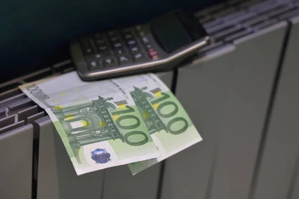 Bir hesap makinesi ve 100 avro banknot ısıtma sisteminin radyatörüne, ısıtma maliyetine, kamu maliyetlerine yatar..