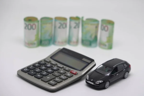 Oyuncak bir araba ve banknotlar mutfak elektronik terazisinde bir hesap makinesinin yanında durur..