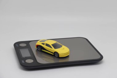 Toy car on kitchen electronic scales, the cost of buying and operating a car.