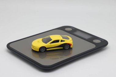 Toy car on kitchen electronic scales, the cost of buying and operating a car.