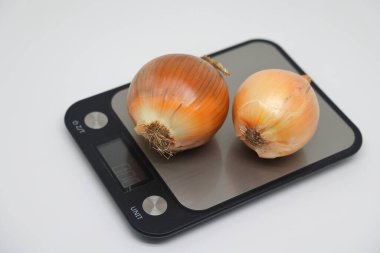Beautiful strong white onion heads on an electronic kitchen scale. Healthy food, diet