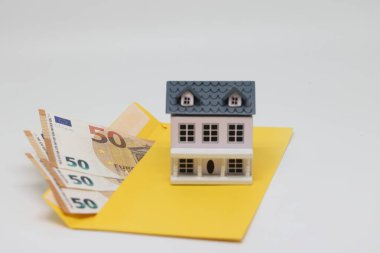 Banknotes in a yellow envelope and a toy house, funds for the purchase of real estate