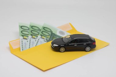 Sarı bir zarf ve oyuncak bir araba içinde banknotlar, araba almak için para.