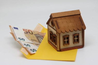 Banknotes in a yellow envelope and a toy house, funds for the purchase of real estate