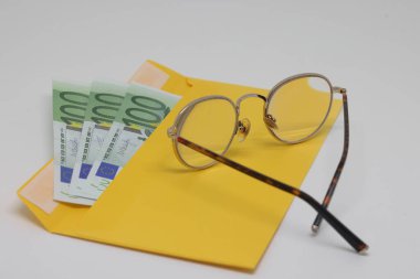 Glasses. banknotes in a yellow envelope. open envelope with banknotes on a light background. envelope with banknotes. close-up of an envelope with cash. international currency banknote. Euro dollars rubles