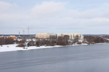 Güneşli bir akşamda nehir. Ağaçlar ve çalılar. Kış manzarası, nehir kıyıları çalılarla kaplı.
