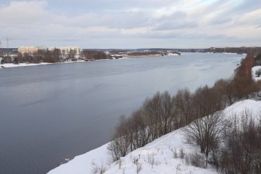 Güneşli bir akşamda nehir. Ağaçlar ve çalılar. Kış manzarası, nehir kıyıları çalılarla kaplı.