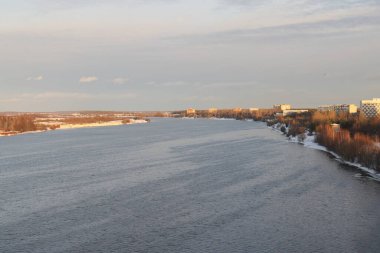 Güneşli bir akşamda nehir. Ağaçlar ve çalılar. Kış manzarası, nehir kıyıları çalılarla kaplı.