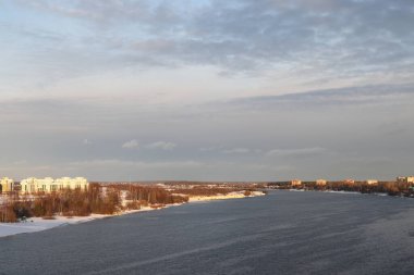 Güneşli bir akşamda nehir. Ağaçlar ve çalılar. Kış manzarası, nehir kıyıları çalılarla kaplı.