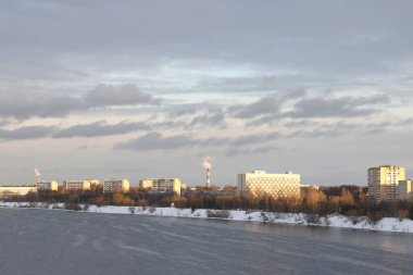 Güneşli bir akşamda nehir. Ağaçlar ve çalılar. Kış manzarası, nehir kıyıları çalılarla kaplı.