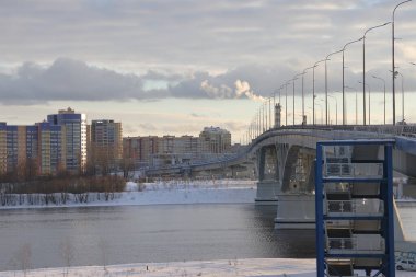 Bridge across the Volga, unfrozen river, winter landscape, snow and bushes along the banks of the river, Russia