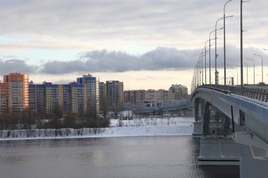 Bridge across the Volga, unfrozen river, winter landscape, snow and bushes along the banks of the river, Russia