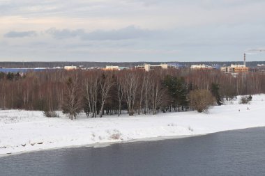 Güneşli bir akşamda nehir. Ağaçlar ve çalılar. Kış manzarası, nehir kıyıları çalılarla kaplı.