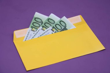 Banknotlar mor arka planda sarı bir zarfın içinde. Rüşvet konsepti. Maaşlar zarflarda. Finansal dolandırıcılık. Kapat.
