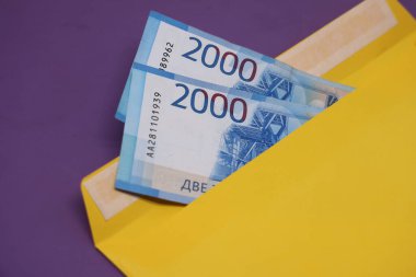 Banknotlar mor arka planda sarı bir zarfın içinde. Rüşvet konsepti. Maaşlar zarflarda. Finansal dolandırıcılık. Kapat.