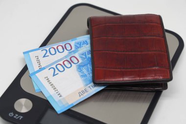 Elektronik mutfak terazilerindeki banknotların olduğu kahverengi cüzdan. Muhasebe ve aile finansmanı planlama sembolü