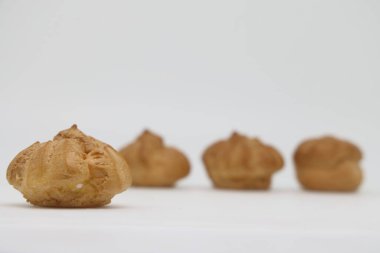 Beyaz arka planda kremalı küçük pastalar. Profiterol. Diyet ve kalori sayımı. Ağırlık denetimi