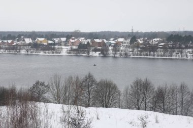 Güneşli bir akşamda nehir. Ağaçlar ve çalılar. Kış manzarası, nehir kıyıları çalılarla kaplı.