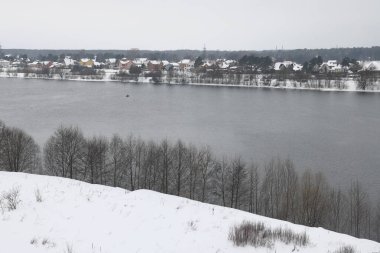 Güneşli bir akşamda nehir. Ağaçlar ve çalılar. Kış manzarası, nehir kıyıları çalılarla kaplı.