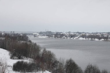 Güneşli bir akşamda nehir. Ağaçlar ve çalılar. Kış manzarası, nehir kıyıları çalılarla kaplı.