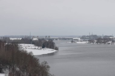 Güneşli bir akşamda nehir. Ağaçlar ve çalılar. Kış manzarası, nehir kıyıları çalılarla kaplı.