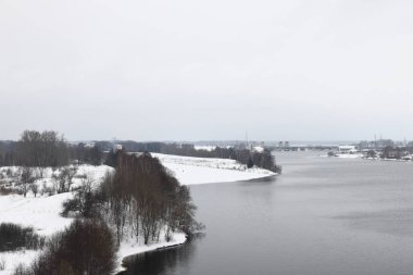 Güneşli bir akşamda nehir. Ağaçlar ve çalılar. Kış manzarası, nehir kıyıları çalılarla kaplı.