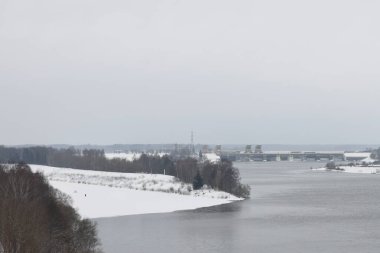 Güneşli bir akşamda nehir. Ağaçlar ve çalılar. Kış manzarası, nehir kıyıları çalılarla kaplı.