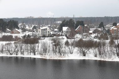 Güneşli bir akşamda nehir. Ağaçlar ve çalılar. Kış manzarası, nehir kıyıları çalılarla kaplı.
